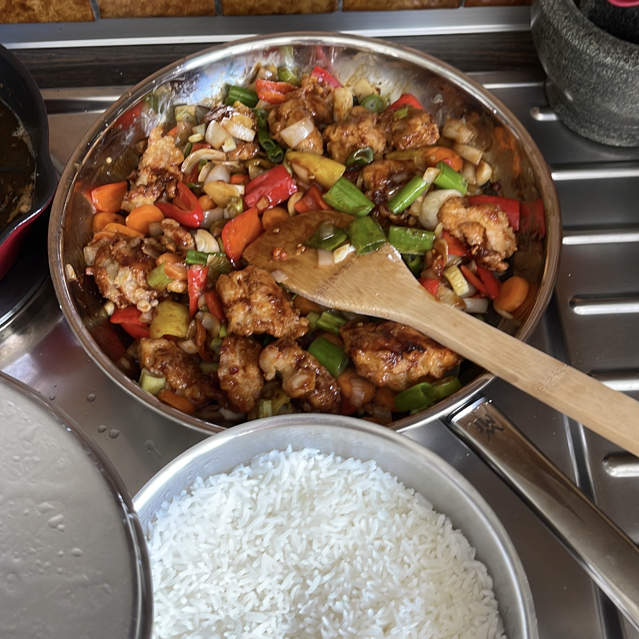 Two pans one filled to the brim with rice and the other one with sweet and sour